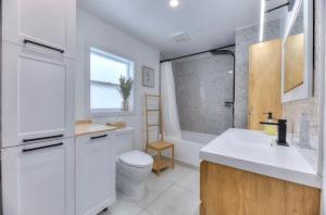 a white bathroom with a toilet and a sink at Great Gaston in Longueuil