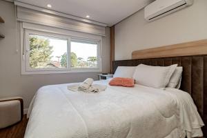 a bedroom with a large white bed with a window at Apto bem próximo do Museu da Nasa in Canela