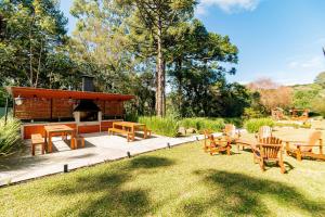 a backyard with a barbecue and wooden tables and chairs at Apto bem próximo do Museu da Nasa in Canela