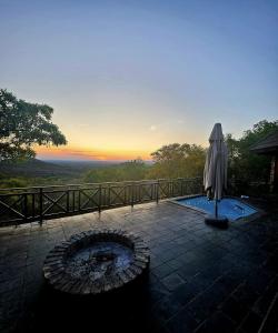 an umbrella sitting next to a pool with the sunset at Mafuta Lodge - Mabalingwe Nature Reserve in Warmbaths