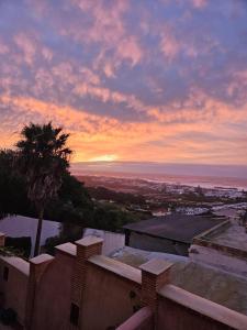 a sunset over a city with a palm tree at SURFLAND APPARTEMENTS Vue sur mer Pour les familles in Oualidia