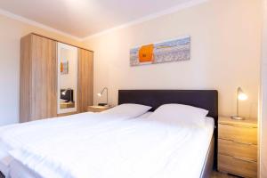 a bedroom with a large white bed and a mirror at _DKK1d_ Ferienwohnung Seemoewe in Niendorf