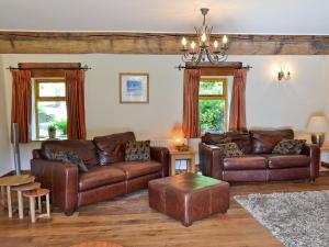 ein Wohnzimmer mit braunen Ledermöbeln und Fenstern in der Unterkunft Lee Cottage in Heptonstall