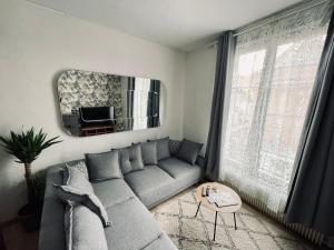 a living room with a gray couch and a mirror at Appartement 80m2 à deux pas du beffroi in Arras