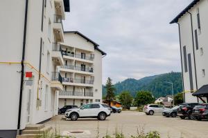 a white car parked in a parking lot next to a building at Arinis Best Bucovina Apartament in Gura Humorului