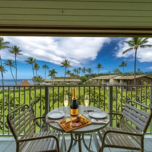 a table with a bottle of wine and a plate of food at Napili Shores G258 Studio Condo condo in Kahana