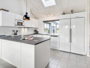 a white kitchen with white cabinets and a refrigerator at 5 star holiday home in Idestrup in Bøtø By