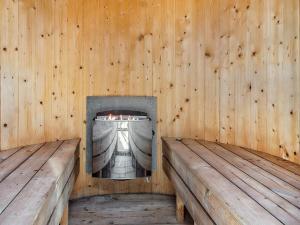 a fireplace in a wooden room with two benches at 5 star holiday home in Idestrup in Bøtø By