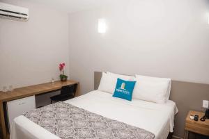 a bedroom with a bed with a blue pillow on it at Ímpar Suítes Expominas in Belo Horizonte +46 photos