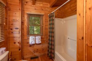a log cabin bathroom with a shower and a tub at Dreams Do Come True by American Patriot Getaways in Cartertown