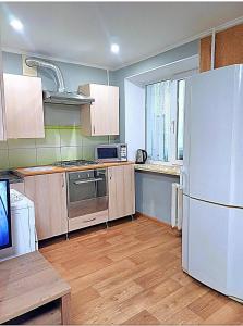 cocina con nevera blanca y suelo de madera en Lux apartment Prospect Central, en Mykolaiv