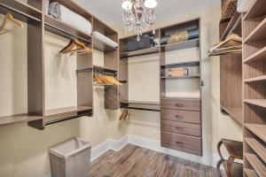 a walk in closet with wooden cabinets and a chandelier at Sea Point #307 in Saint Simons Island +30 photos