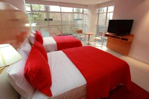 a bedroom with a red and white bed and a television at Pascana Hotel in Santa Cruz de la Sierra