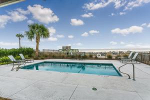 a swimming pool with two chairs and a palm tree at Sea Point #205 in Saint Simons Island