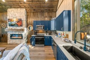 een keuken met blauwe kasten en een stenen open haard bij Anchors Retreat - Lakefront Getaway for 14 Guests in Sevierville