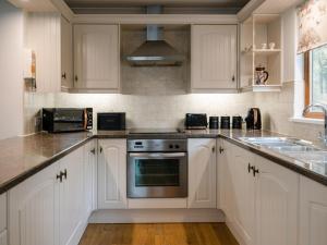 a kitchen with white cabinets and a stove top oven at Fir Tree Lodge in Sewerby +10 photos