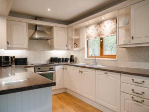 a kitchen with white cabinets and a sink and a window at Fir Tree Lodge in Sewerby