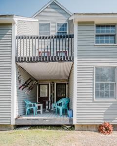 a house with a deck with two chairs and a table at Cozy Condo, Minutes from Sunday River in Bethel