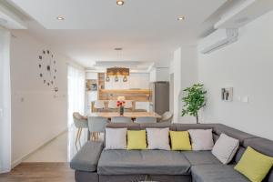 ein Wohnzimmer mit einem grauen Sofa und gelben Kissen in der Unterkunft Villa Zlatne NiTi with heated pool in Kaštela