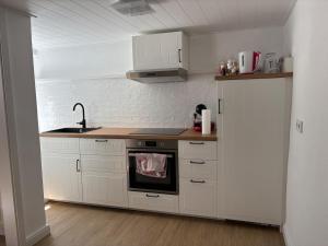 a kitchen with white cabinets and a sink and a stove at Cozy tiny house in Kyllburg