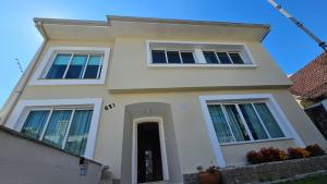 库里提巴Hospedagem Central Curitiba - O seu lar longe de casa的白色的房子,设有两扇窗户和一扇门