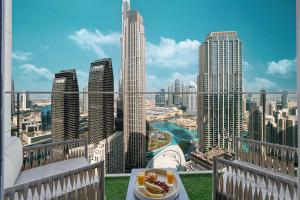 ドバイにあるStunning Downtown 4BR Sky High Luxury Apartment with Fountain Viewsの街のスカイラインが見えるバルコニーのテーブルに置かれた料理