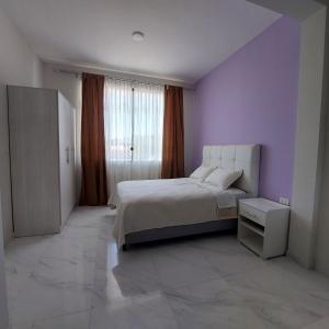 a bedroom with a bed and a purple wall at Amplio departamento en Tarija con terraza y garaje in Tarija
