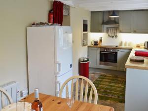a kitchen with a wooden table and a white refrigerator at Sunloch Cottage in St Just
