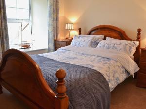 a bedroom with a large bed with a wooden frame at Sunloch Cottage in St Just