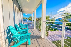 Un porche con bancos azules con vista al agua. en Blue Horizon Golf Cart Pool & Sleeps 32, en Santa Rosa Beach