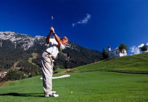 un hombre balanceando un club de golf en un campo de golf en BUSSLEHNER Apartments, en Achenkirch