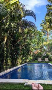 チャングーにあるThe Belong Canggu Bali By SDM Managementのスイミングプール横の芝生の上に横たわる者