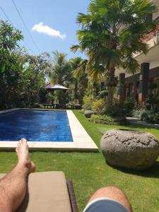 チャングーにあるThe Belong Canggu Bali By SDM Managementのスイミングプール横のベンチに横たわる男 +10枚の写真