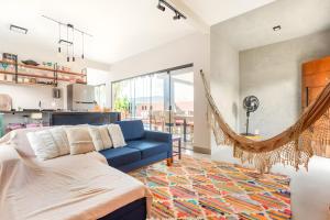 a living room with a blue couch and a hammock at Casa com piscina, vista das montanhas, terraço, quintal in Pirenópolis