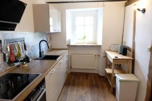 a small kitchen with white cabinets and a window at Ferienwohnung Fränkischer Hof in Kail