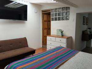 a bedroom with a bed and a couch and a flat screen tv at Hatuchay Inka Apart Hotel in Cajamarca