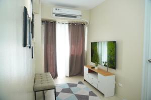 伊洛伊洛Luxury Suite的一间带电视、椅子和梳妆台的客厅