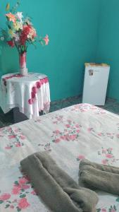 - un lit avec une table et un vase de fleurs dans l'établissement Chácara nossa senhora de Nazaré, à Benfica