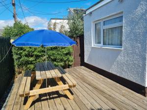 - une table de pique-nique en bois avec un parasol sur la terrasse dans l'établissement Sandy Cottage, à Clacton-on-Sea