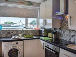 a kitchen with a washing machine and a window at Top Croft in Beadnell