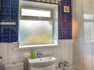 a bathroom with a sink and a window and a toilet at Top Croft in Beadnell +5 photos