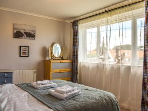 a bedroom with towels on a bed in front of a window at Top Croft in Beadnell