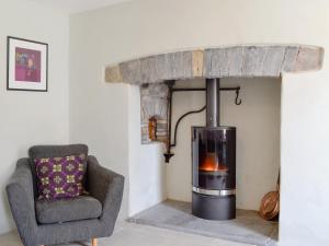 a living room with a wood stove and a chair at The Mill Farmhouse in Llandybie