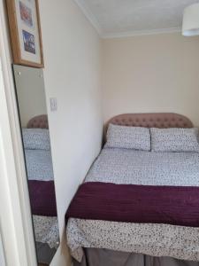 une petite chambre avec un lit et un miroir dans l'établissement Sandy Cottage, à Clacton-on-Sea