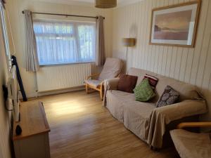 un salon avec un canapé et une chaise dans l'établissement Sandy Cottage, à Clacton-on-Sea