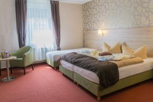 una habitación de hotel con 2 camas y una silla en Hotel zur Post in Wurzen, en Wurzen