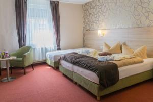 ein Hotelzimmer mit 2 Betten und einem Stuhl in der Unterkunft Hotel zur Post in Wurzen in Wurzen