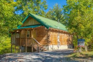 a log cabin with a green roof and a porch at Forever Yours by American Patriot Getaways in Cove Creek Cascades +12 photos