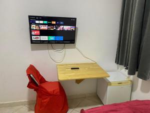 a room with a tv on a wall with a red chair at Hotel Soukina in Dakhla