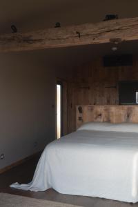 a bedroom with a white bed with a wooden wall at 'SLOE at Daniels in Gloucestershire